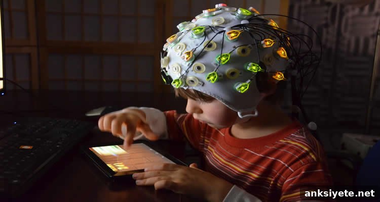 The image shows a child with an EEG cap on their head. The child is playing with a computer tablet.