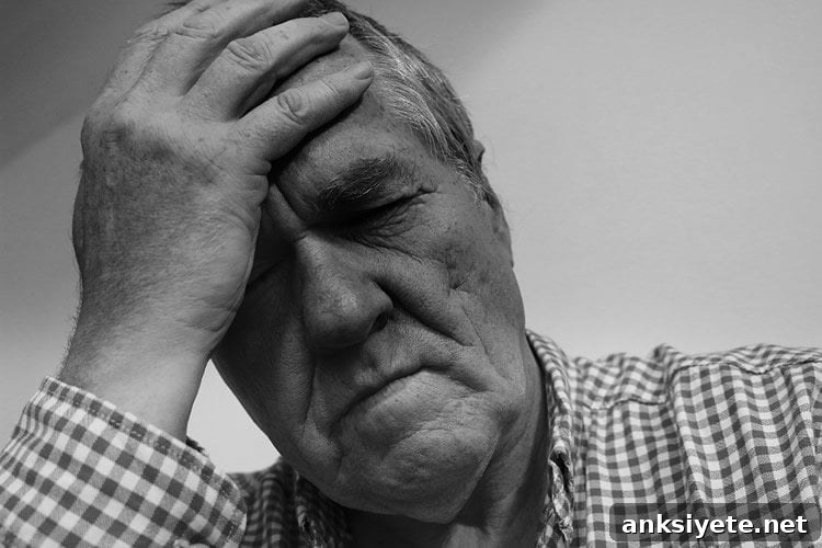 Image shows an older man holding his head in pain.
