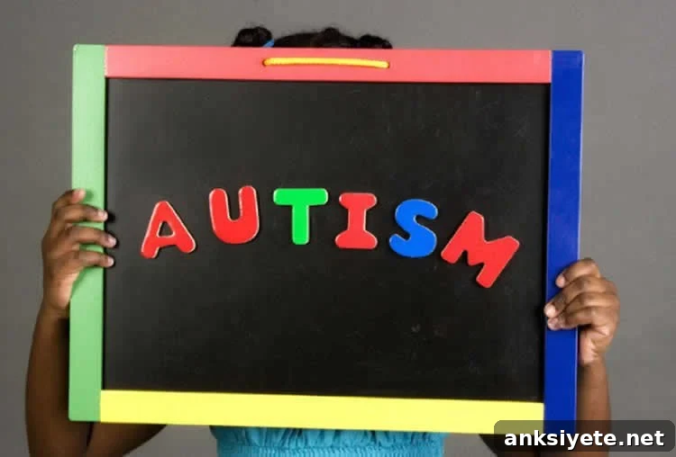 Image shows a girl holding up a sign with the word Autism on it.
