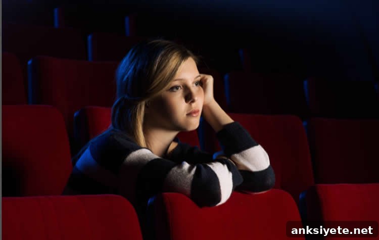 Image shows a sad looking woman in a movie theatre.