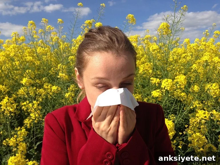 This shows a woman sneezing into a tissue in a field of yellow flowers